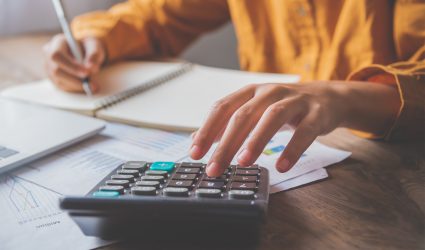 business person sitting at a desk at an office By using the calculator to work. Business Concept Analysis and Planning